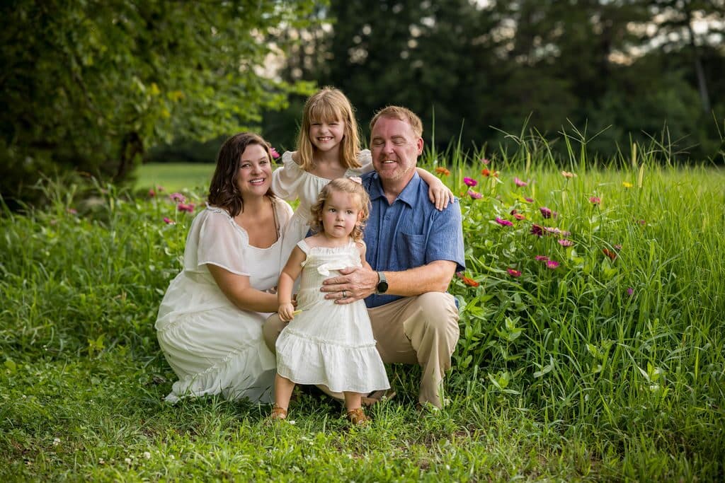 A family of four in a summer wildflower field at golden hour
